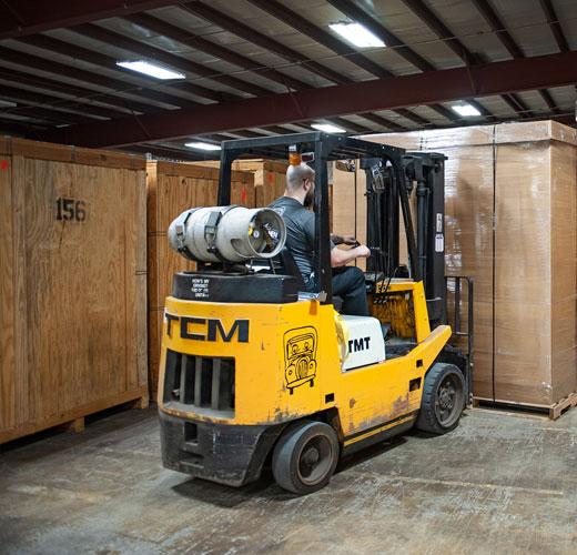 A team member on a forklift moving a crate
