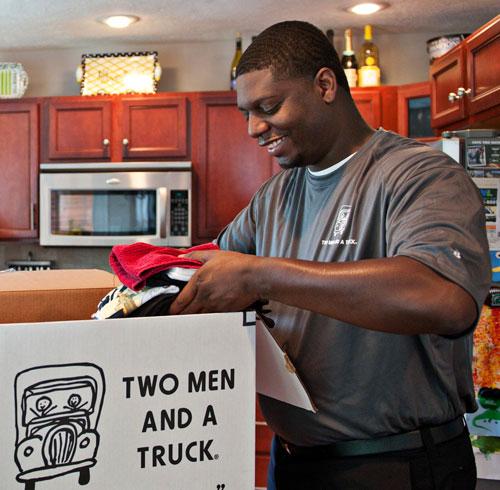 two men and a truck professional company mover packing a box