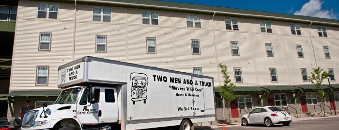 Two men and a truck parked in front of an apartment