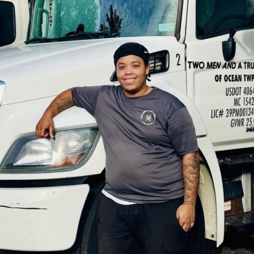 Jhahad standing with his arm on one of our moving trucks
