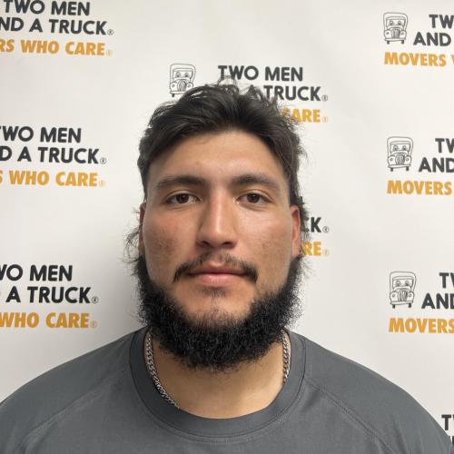 driver david rivera standing in front of two men and a truck logo background wearing grey shirt
