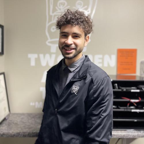 felipe is standing in front of a desk with his mover uniform on, smiling