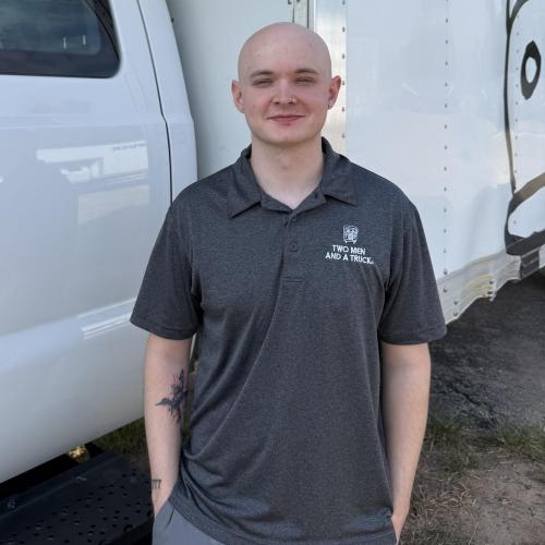 Moving company customer service representative standing in the truck lot getting photo taken 