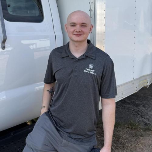 Customer service representative standing in front of a moving truck. 