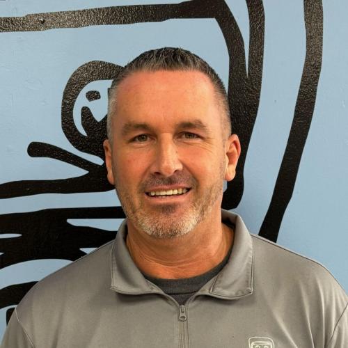 Craig is standing in front of a blue wall smiling