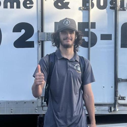Tanori standing in front of a moving truck giving a thumbs up