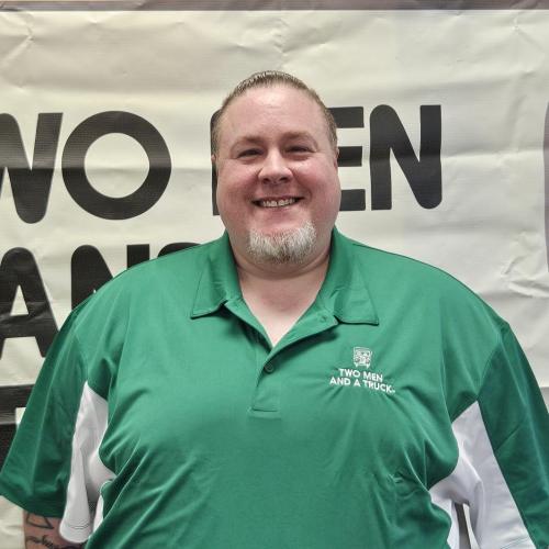 Man in green shirt in front of business sign indoors