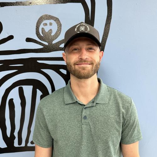 quinn is wearing a hat smiling in front of a blue wall
