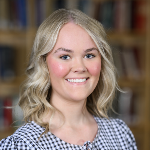 erika's professional headshot. She is smiling at the camera and wearing a gingham blouse.