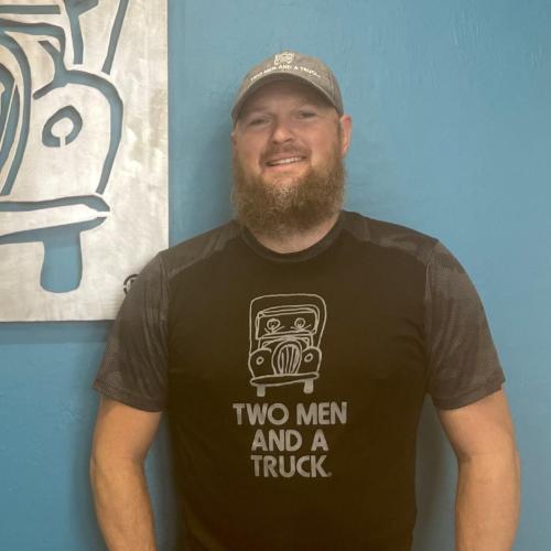 Warehouse Manager, Stephan standing in front of Two Men sign