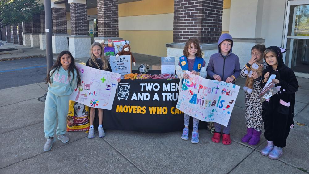 Image of Girl Scout troops holding signs to make donations to Stuff a Truck for Pets