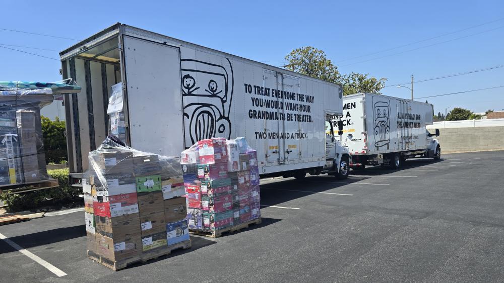 TWO MEN AND A TRUCK trucks parked next to pallets of supplies.