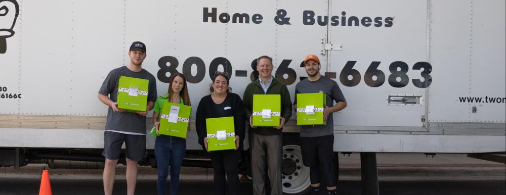TWO MEN AND A TRUCK® crew, Cheeriodicals, and Scottish Rite employees standing in front of TWO MEN AND A TRUCK® truck holding green boxes