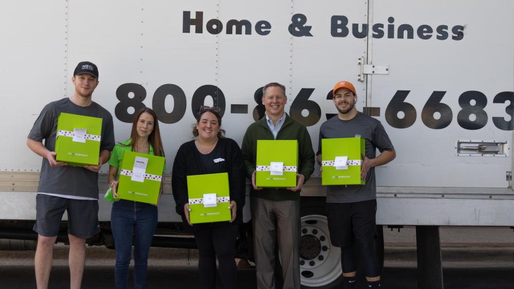 TWO MEN AND A TRUCK® crew, Cheeriodicals, and Scottish Rite employees standing in front of TWO MEN AND A TRUCK® truck holding green boxes