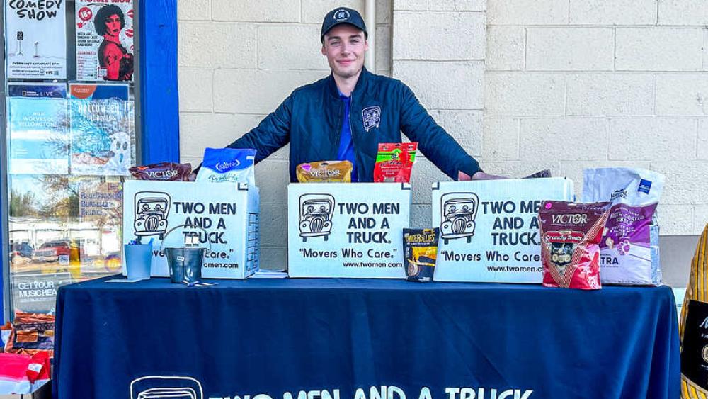 a mover standing behind a table full of pet donations