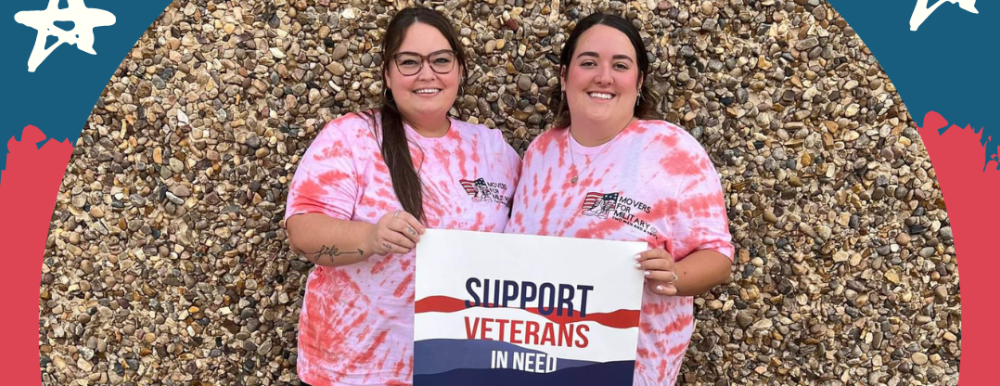 two women standing in front of rock wall wearing red tie dye shirts holding sign for veterans