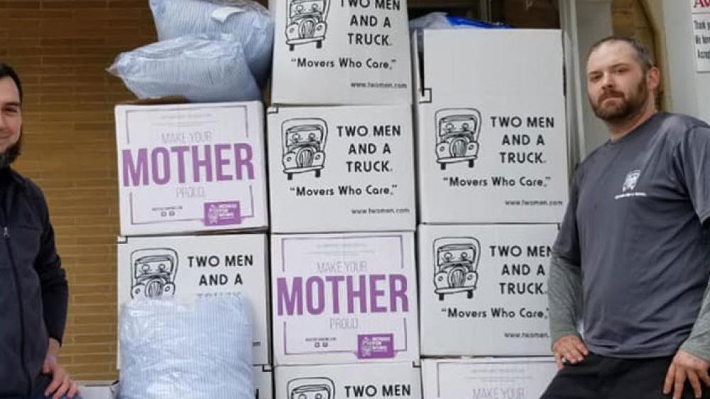 two men and a truck mover with aware shelter volunteer standing in front of donation boxes
