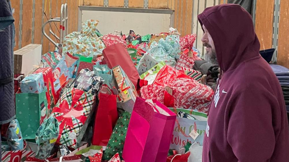 a man walking in front of the back of a truck filled with presents