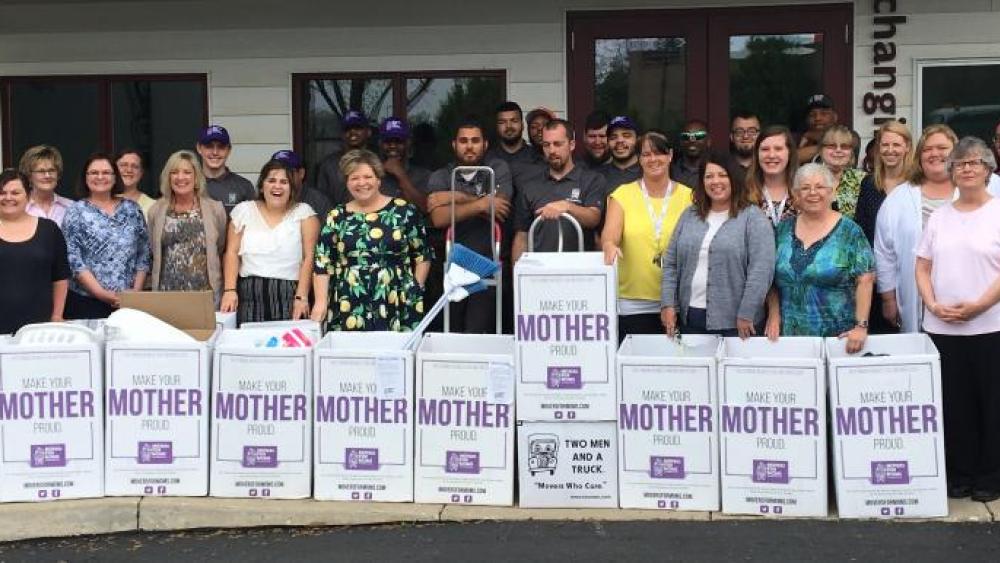 Staff members standing behind movers for moms donation boxes.