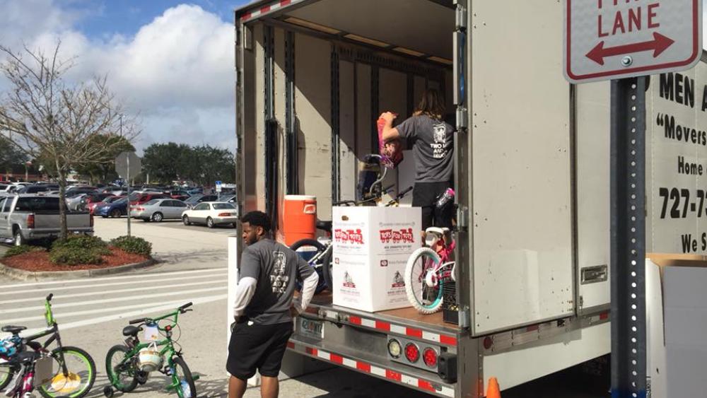 Movers putting Toys for Tots boxes into TWO MEN AND A TRUCK truck