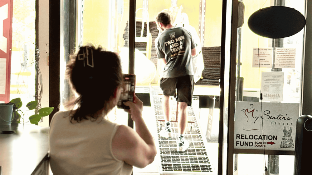 photo of movers carrying items up ramp into truck, and owner taking photo
