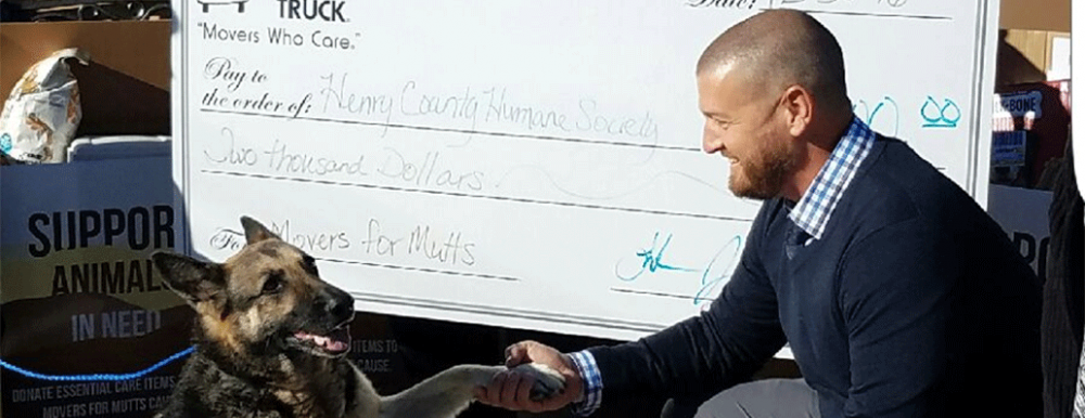 two men and a truck presenting the humane society with a large size donation check