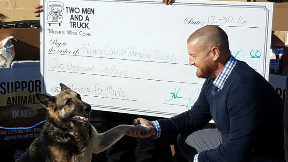 two men and a truck presenting the humane society with a large size donation check