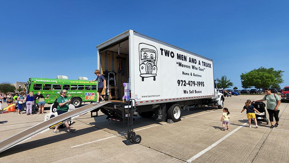 TWO MEN AND A TRUCK® truck parked in parking lot with kids and parents exploring truck