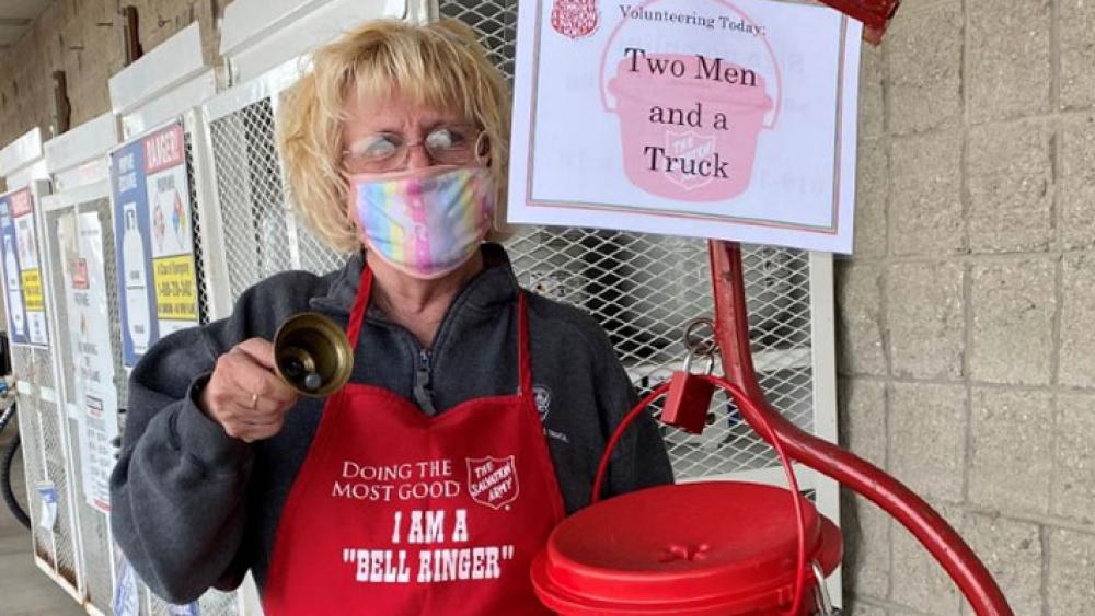 salvation army volunteer ringing a bell, the bell stand reads "two men and a truck"