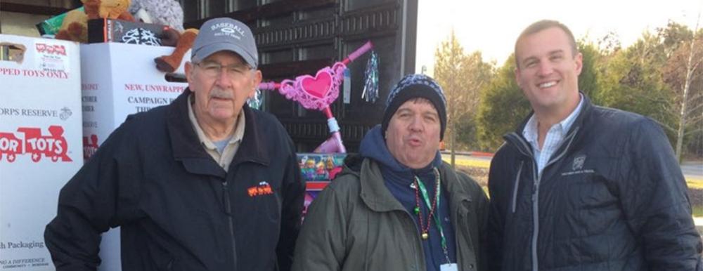 two men and a truck employees with toys for tots staff posing for a photo