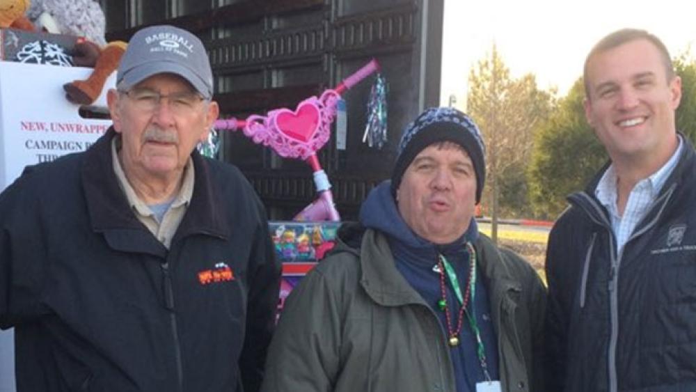 two men and a truck employees with toys for tots staff posing for a photo