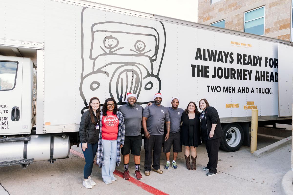 TWO MEN AND A TRUCK Dallas movers standing in front of truck with Toys for Tots of Collin County at Childrens Hospital of Plano