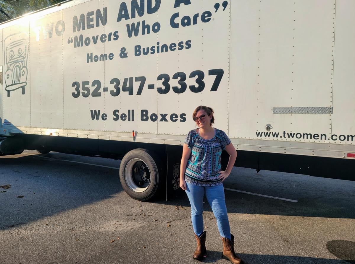 Woman standing in front of company moving truck