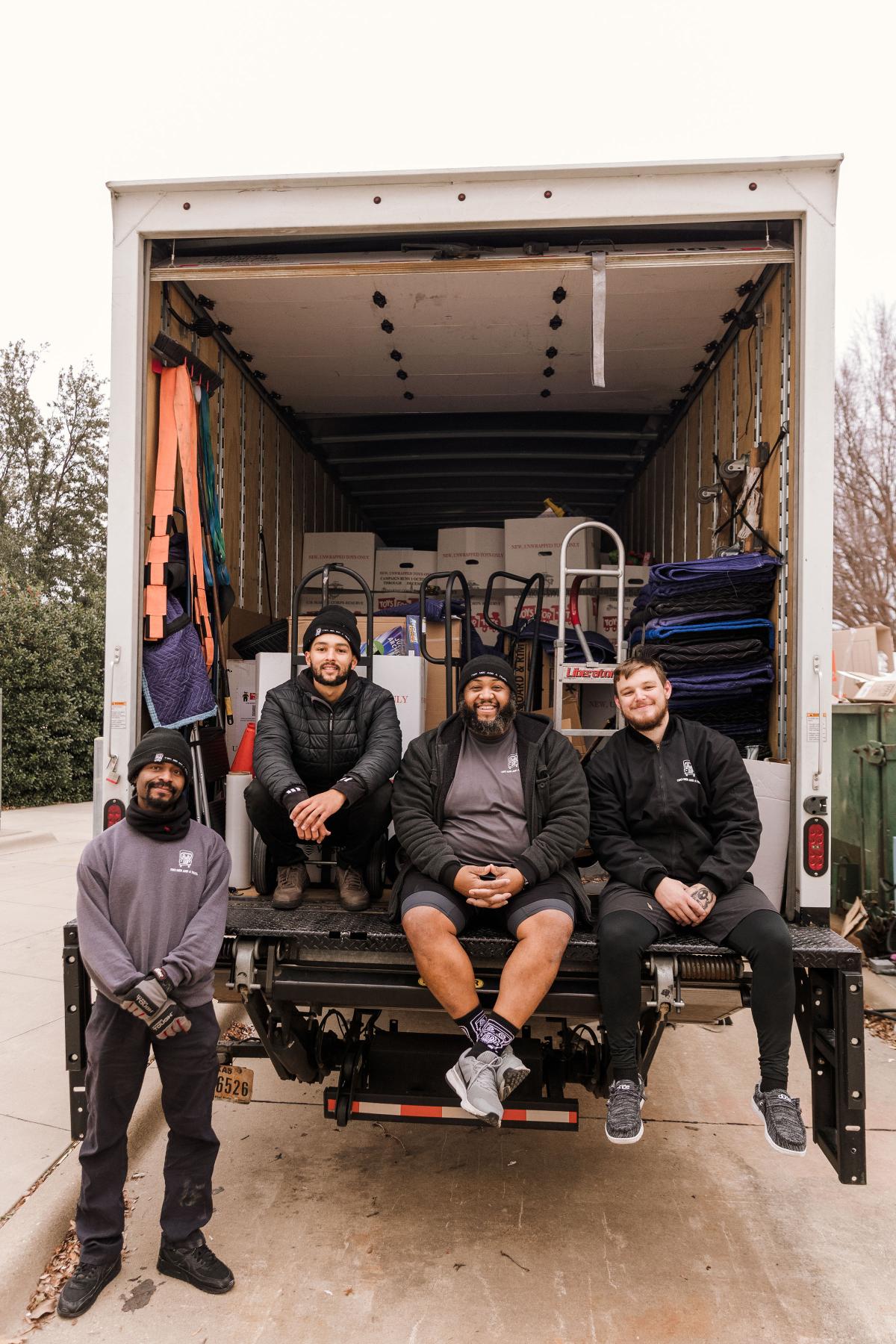 TWO MEN AND A TRUCK EMPLOYEES SITTING ON THE BACK OF TRUCK IN WINTER GEAR