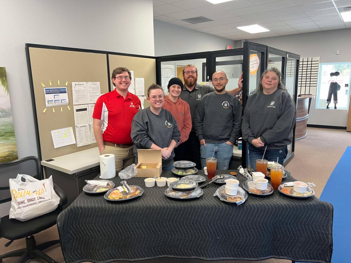 people standing in office in front of table with food