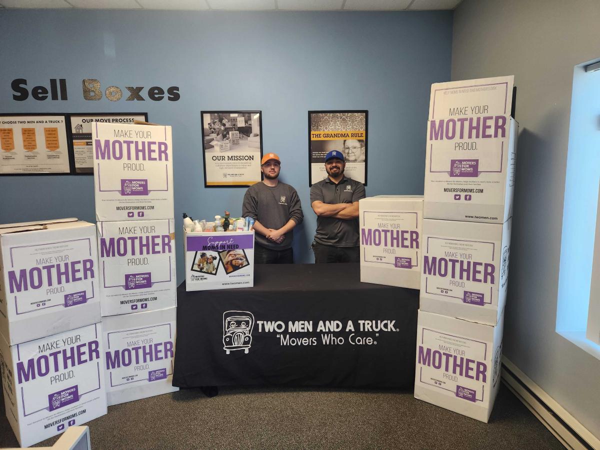 two movers with boxes of donations and a table with donations on top of it