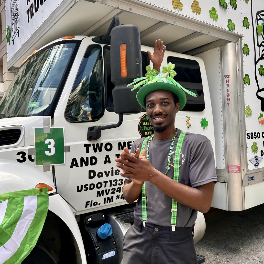 Two Men And A Truck mover walking in the Fort Lauderdale St. Patrick's Day Parade next to truck