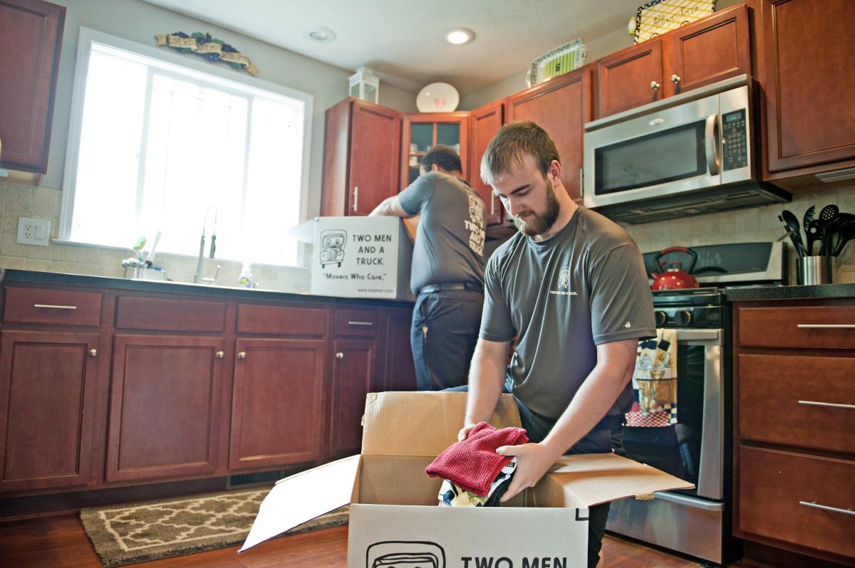 two men and a truck movers packing items in a kitchen