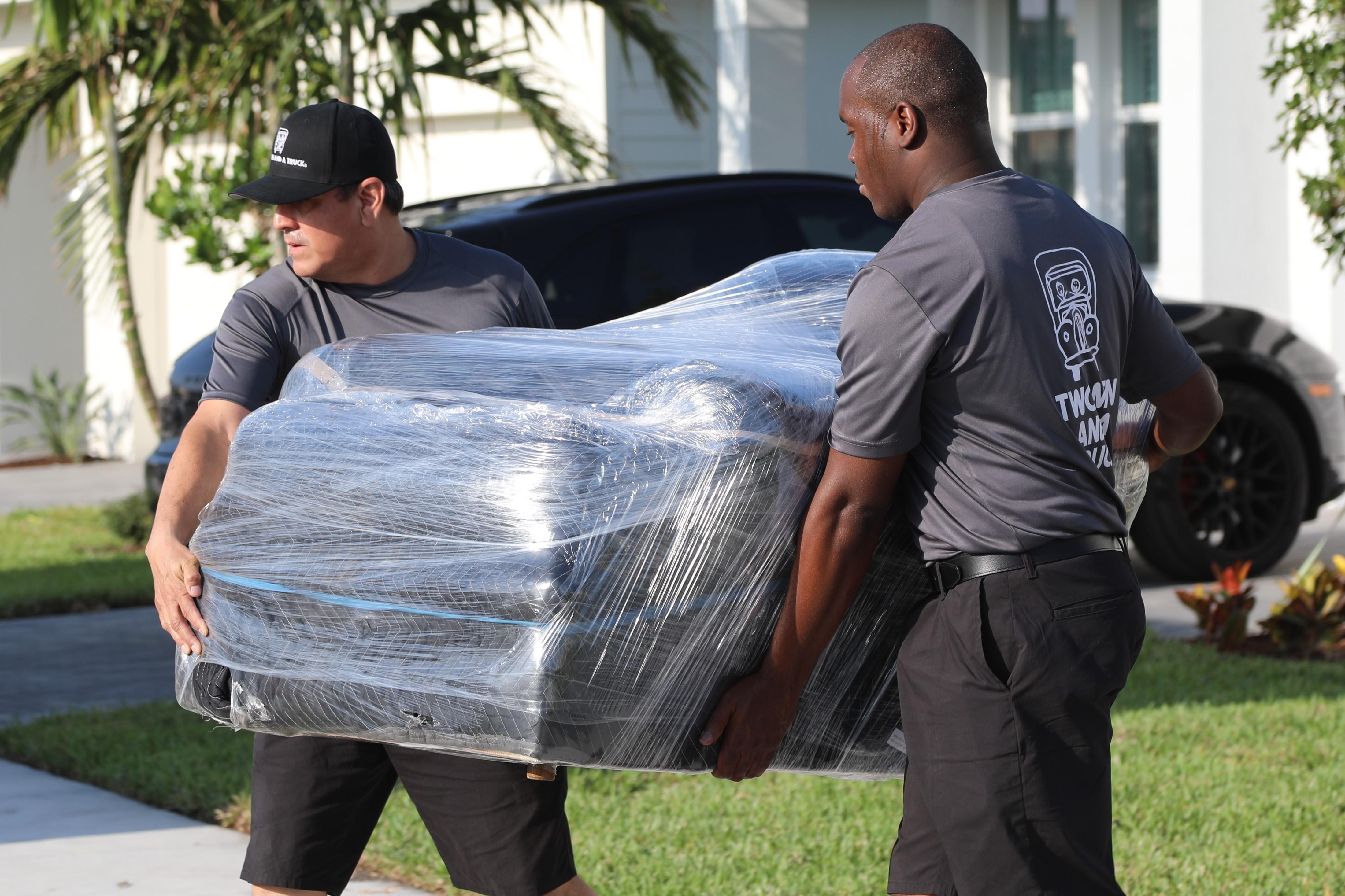 TWO MEN AND A TRUCK carrying wrapped furniture 