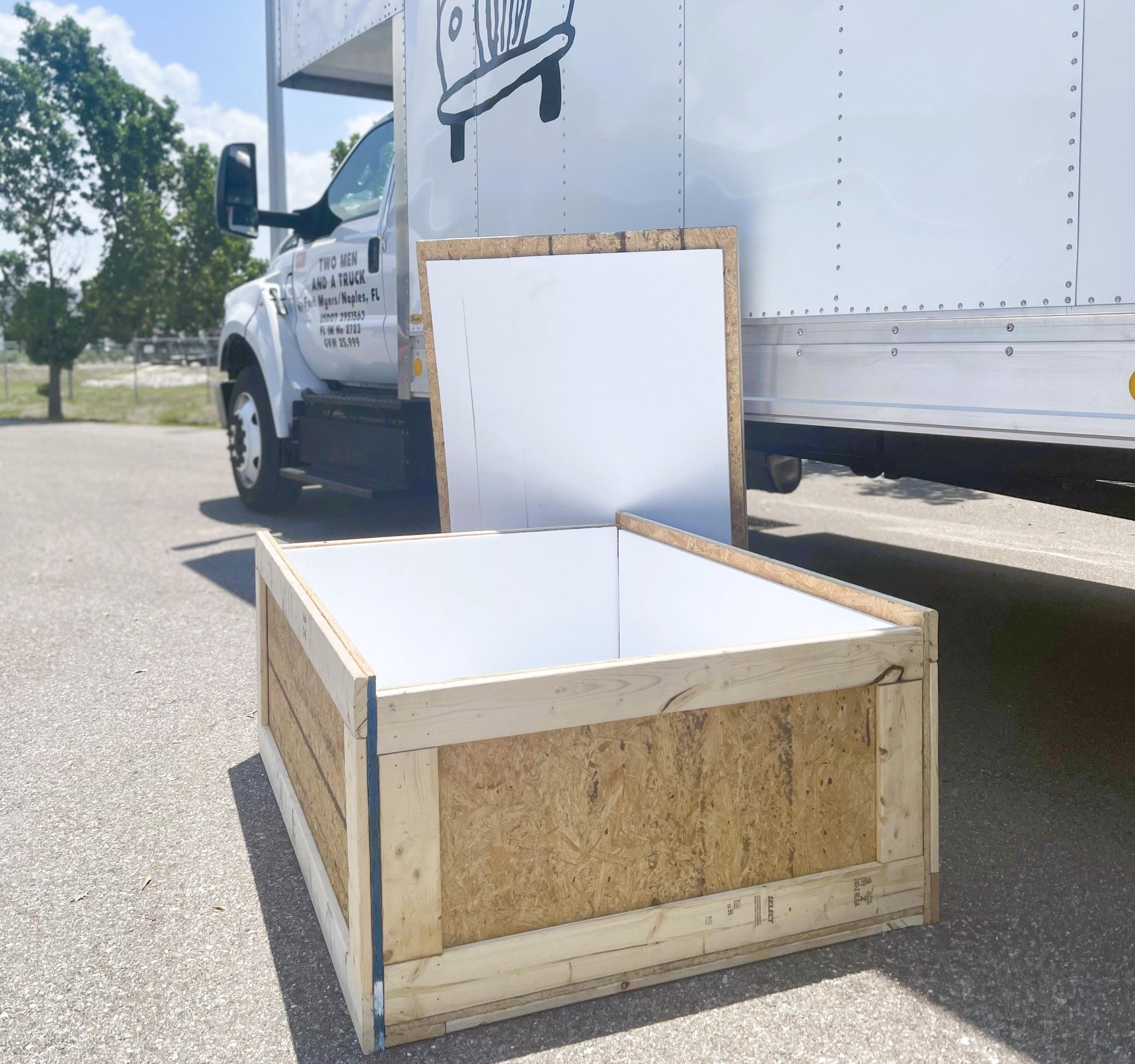 Moving crate shown on the ground, opened next to a moving truck