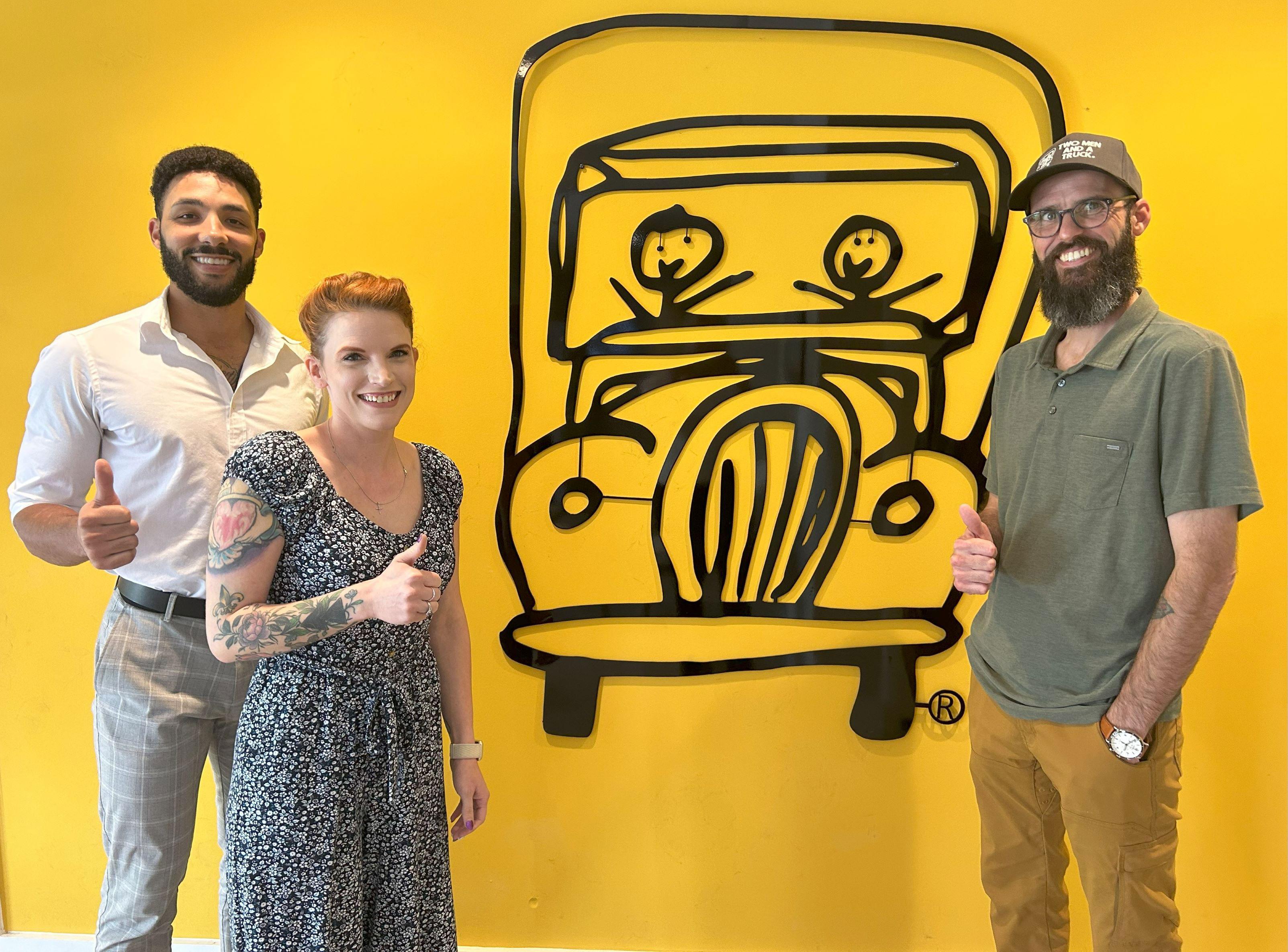 Midtown Atlanta moving team in front of a yellow background with the two men and a truck company logo