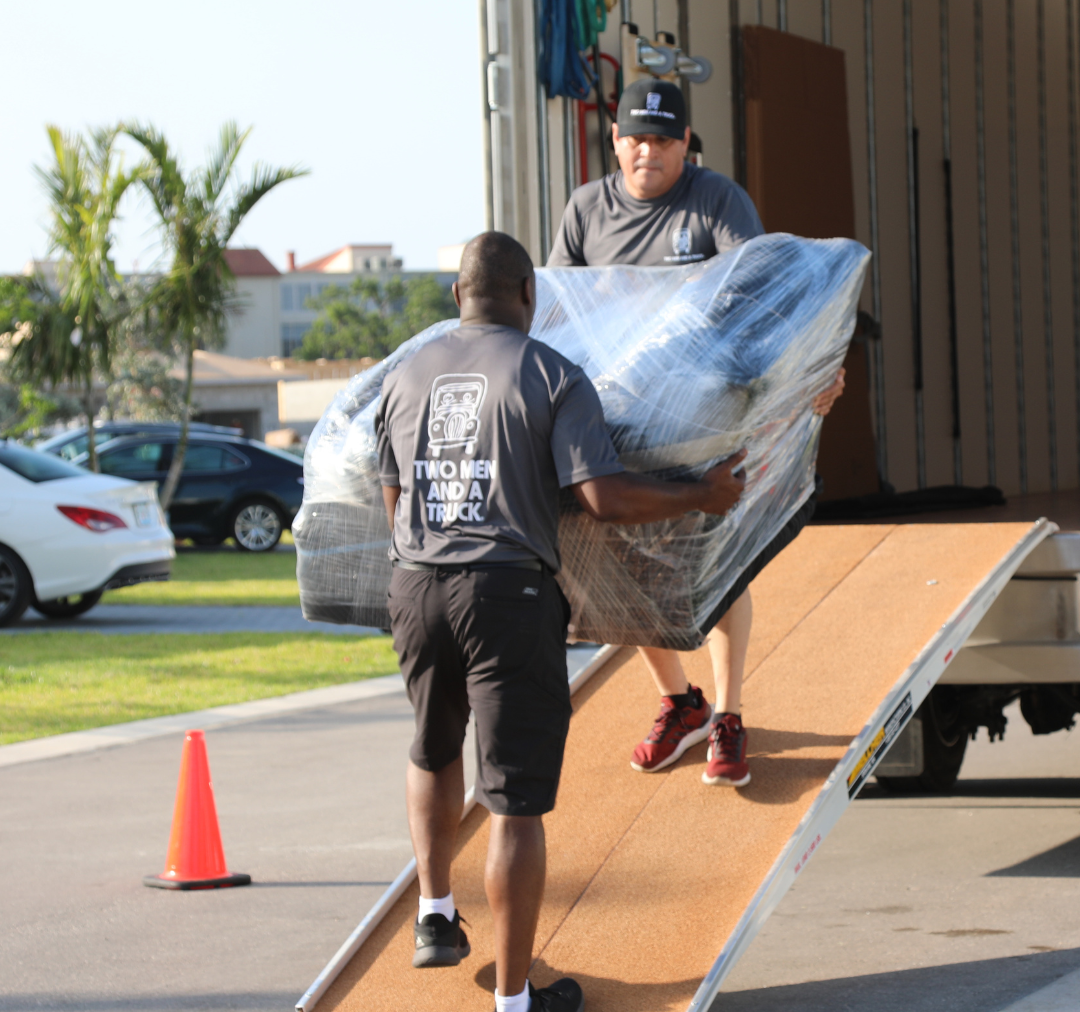 two movers loading a mattress onto a truck