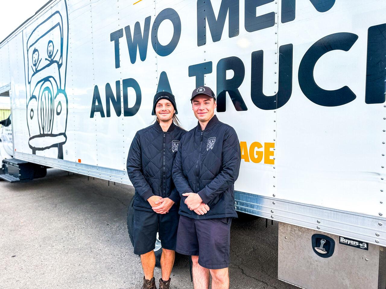 two movers standing in front of a moving truck
