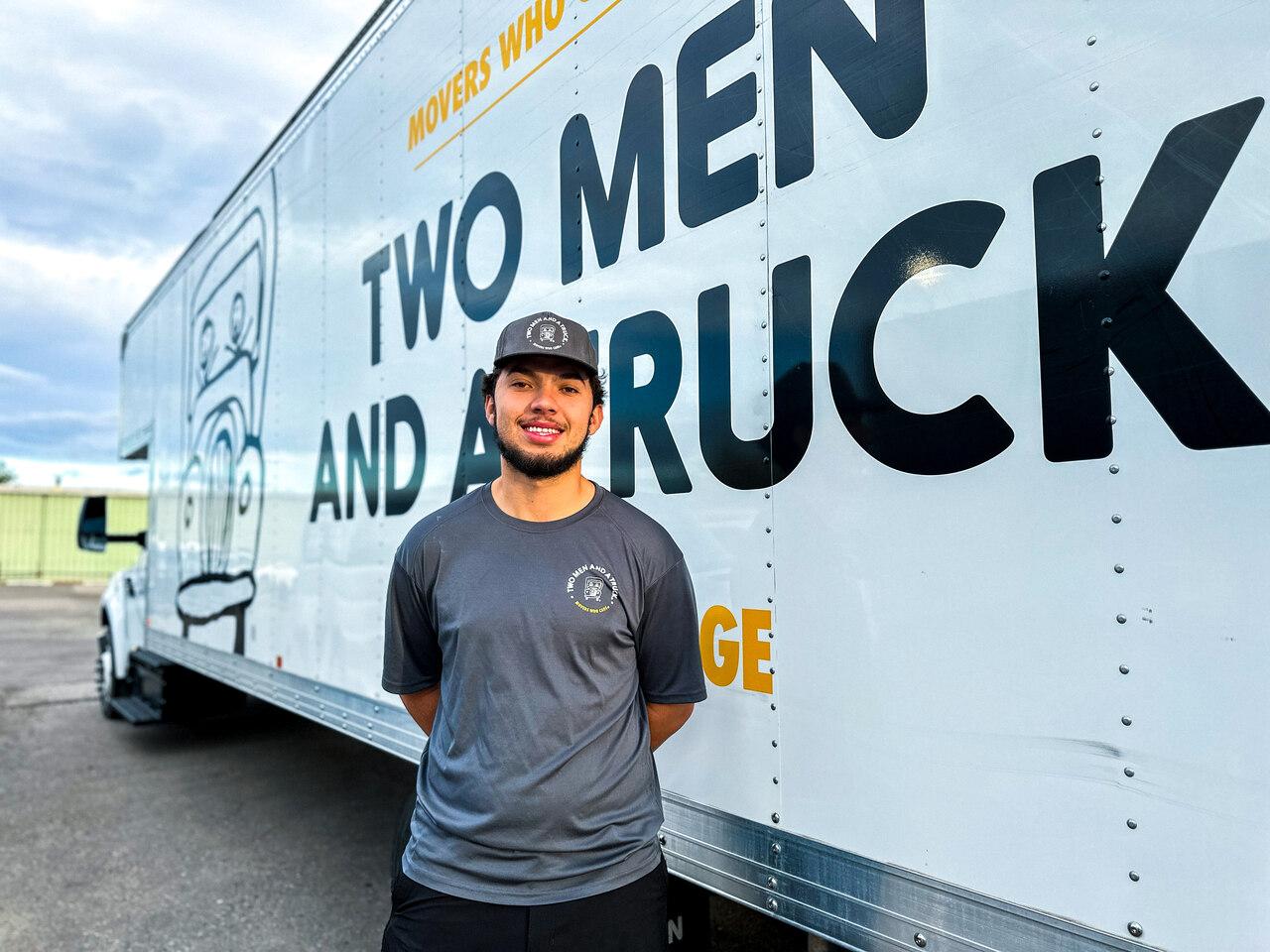 trevor is in his mover uniform standing in front of a moving truck