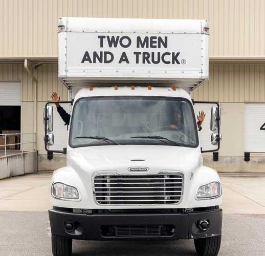 Two movers in a truck waving out the windows