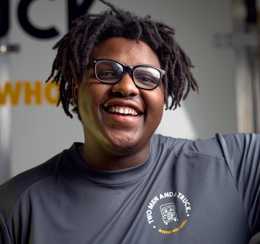 deondre is smiling in front of the back of a moving truck