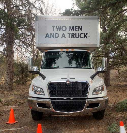 Moving truck in a wooded area surrounded by traffic cones
