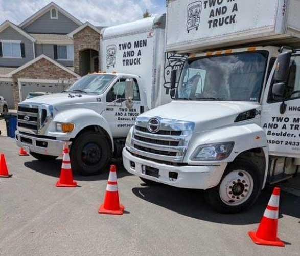 trucks parked in front of a home with road cones in front of the trucks