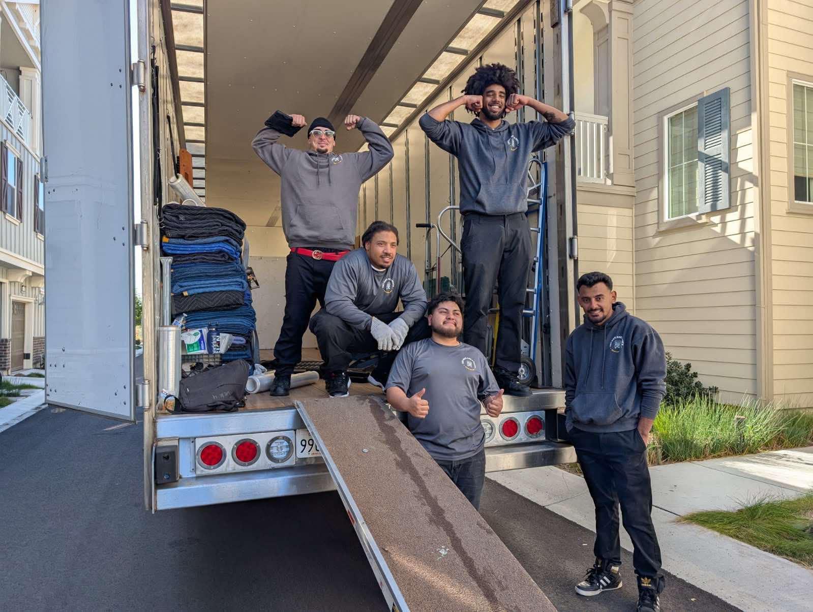 movers posing for a picture on the back of a truck