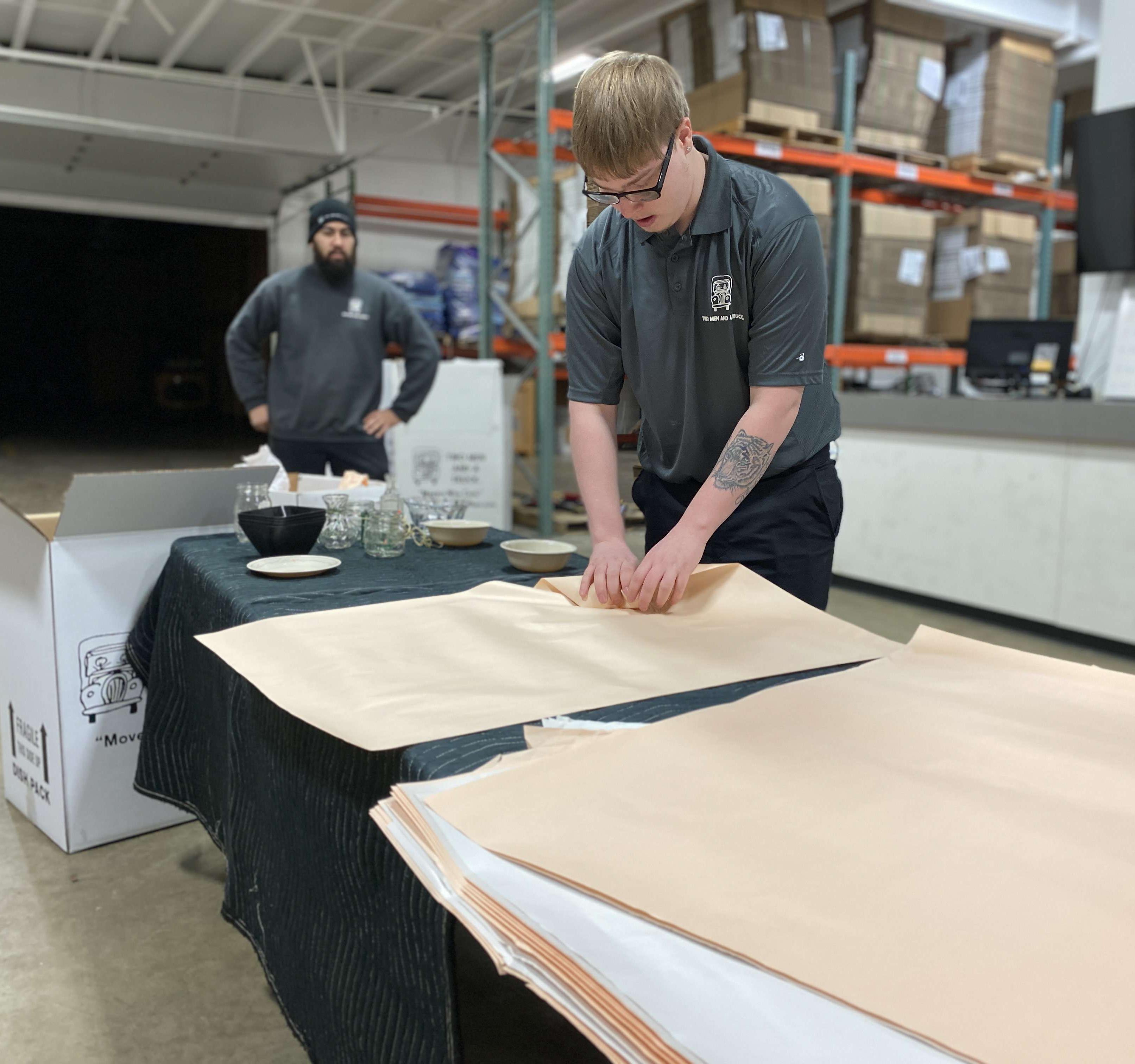 Trainee learning how to protect dishes with packing paper